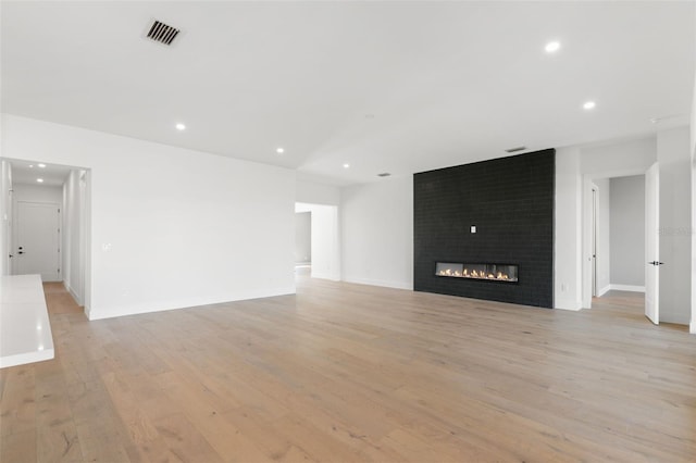1810 4th St E, Palmetto, FL 34221 - unfurnished living room with light wood-type flooring, recessed lighting, a large fireplace, and baseboards
