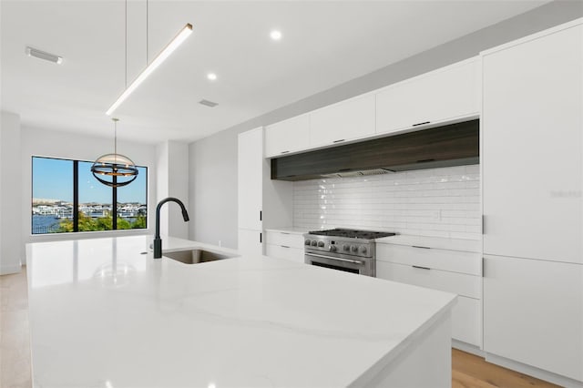 kitchen featuring a kitchen island with sink, high end stainless steel range, sink, white cabinets, and light hardwood / wood-style floors