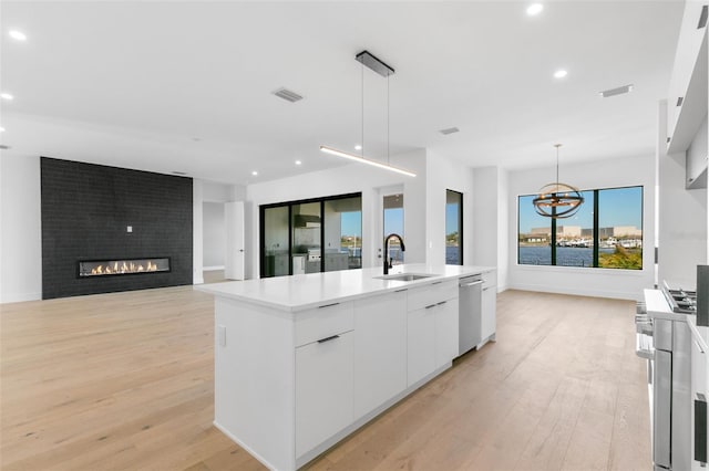 1810 4th St E, Palmetto, FL 34221 - kitchen featuring a sink, appliances with stainless steel finishes, light wood finished floors, white cabinetry, and a center island with sink