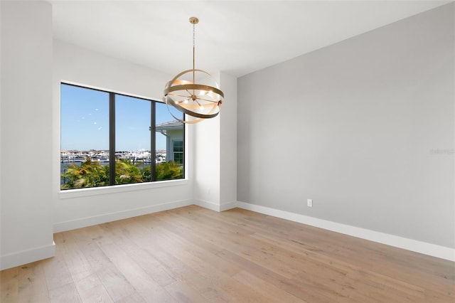 1810 4th St E, Palmetto, FL 34221 - unfurnished room with a chandelier, light wood finished floors, and baseboards