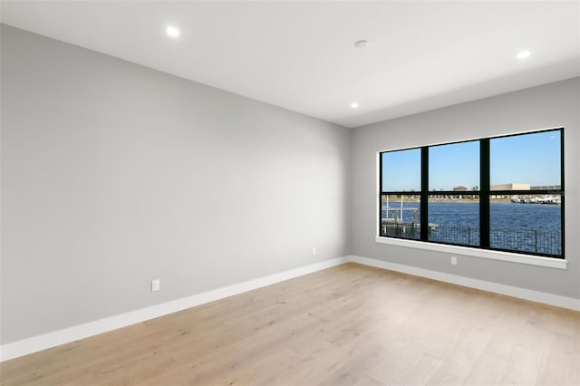 empty room with light hardwood / wood-style flooring and a water view