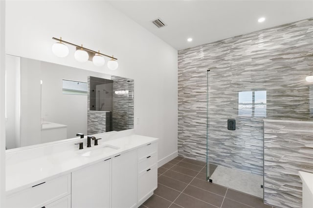 bathroom with vanity, a healthy amount of sunlight, tiled shower, and tile patterned flooring