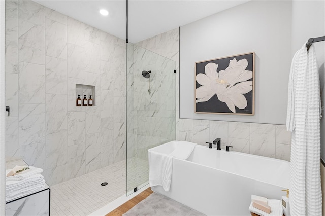 bathroom with wood-type flooring, tile walls, and independent shower and bath