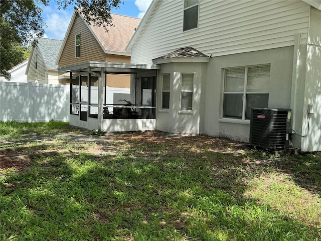 back of property with central AC, a yard, and a sunroom