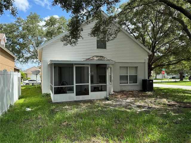 rear view of property featuring a sunroom, central AC unit, and a yard