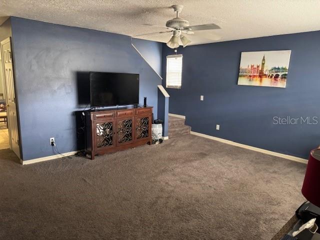 carpeted living room featuring ceiling fan and a textured ceiling