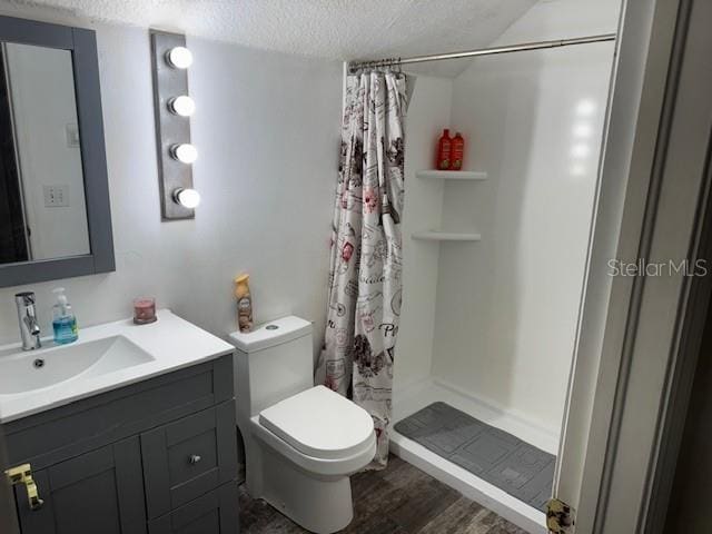 bathroom featuring toilet, a shower with shower curtain, vanity, hardwood / wood-style flooring, and a textured ceiling