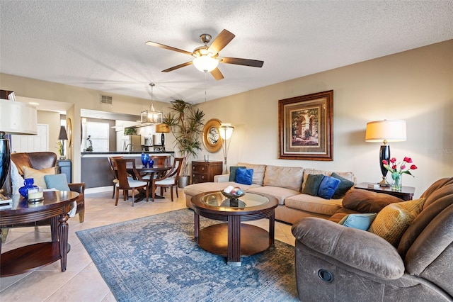 living room with ceiling fan, a textured ceiling, and light tile patterned floors