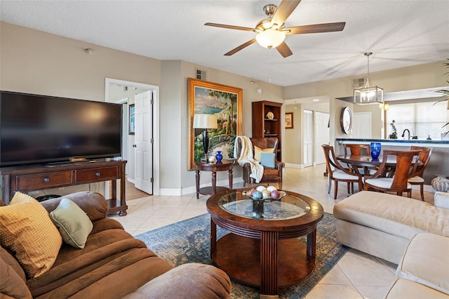 tiled living room featuring ceiling fan with notable chandelier and a textured ceiling