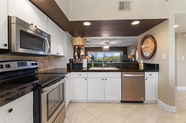 kitchen with appliances with stainless steel finishes, sink, light tile patterned floors, and white cabinetry