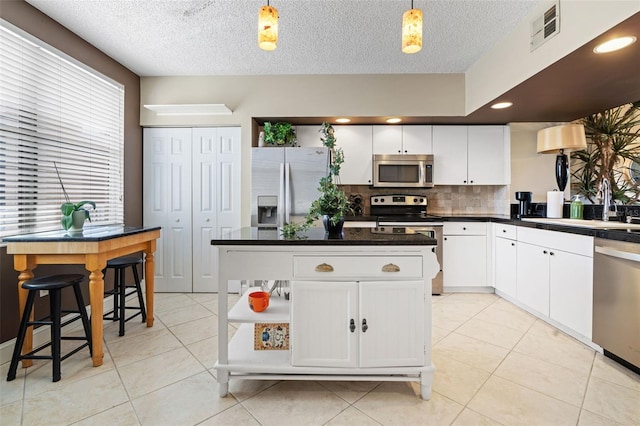 6450 Shoreline Dr Unit 9105, Saint Petersburg, FL 33708 - kitchen featuring visible vents, white cabinetry, a sink, stainless steel appliances, and light tile patterned flooring
