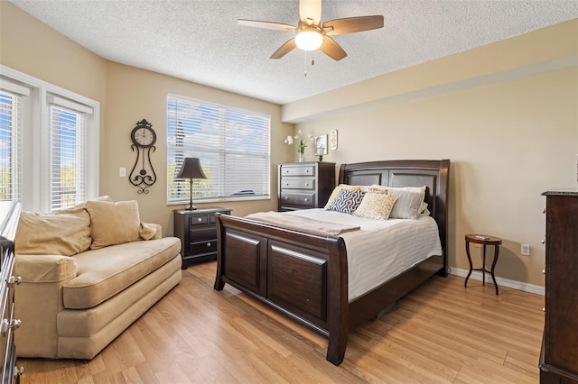 bedroom featuring light wood-type flooring, ceiling fan, and a textured ceiling