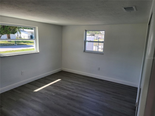 empty room featuring a textured ceiling and dark hardwood / wood-style flooring