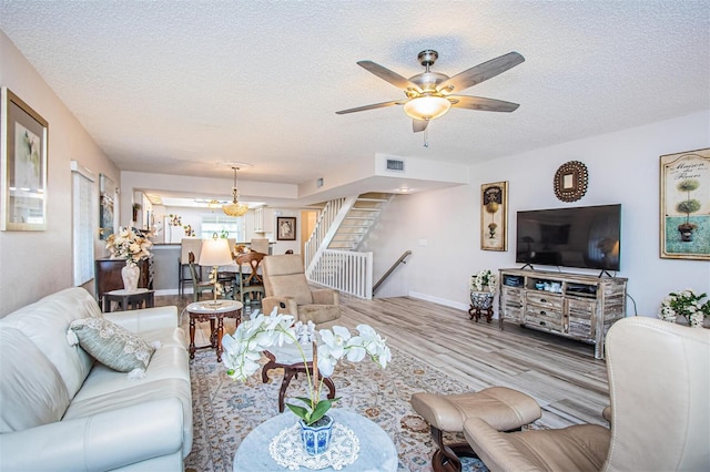 living room with light hardwood / wood-style flooring, a textured ceiling, and ceiling fan