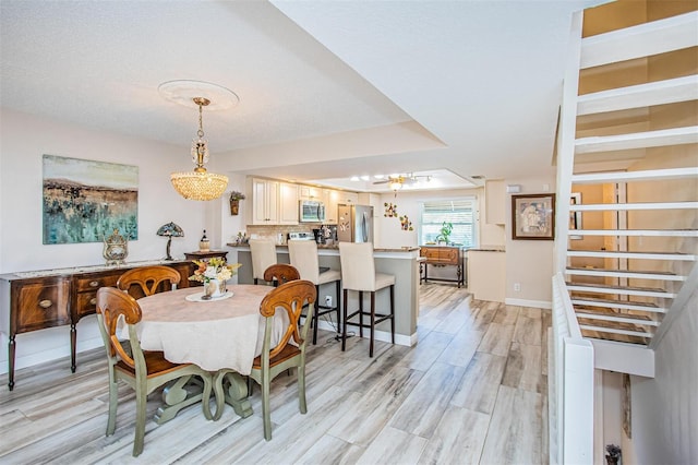 dining area featuring an inviting chandelier, light hardwood / wood-style flooring, and a textured ceiling