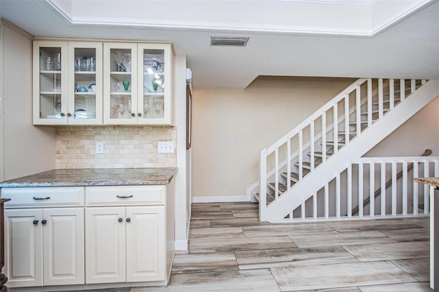 kitchen featuring light hardwood / wood-style flooring, white cabinetry, light stone counters, and backsplash