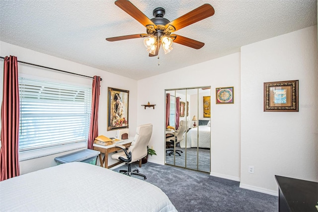 bedroom featuring a textured ceiling, a closet, ceiling fan, vaulted ceiling, and dark colored carpet