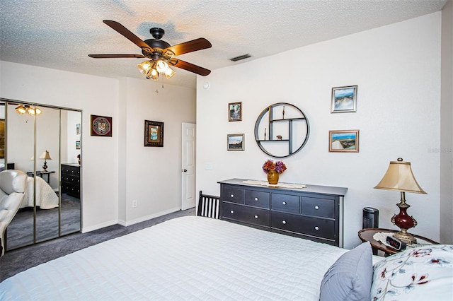 bedroom featuring dark colored carpet, a textured ceiling, a closet, and ceiling fan