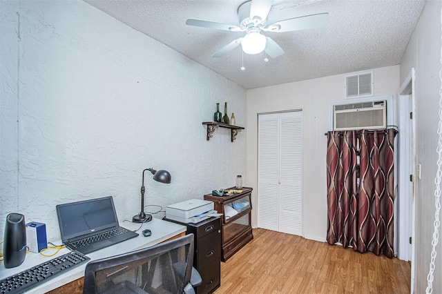 office area featuring a wall mounted AC, a textured ceiling, light hardwood / wood-style floors, and ceiling fan