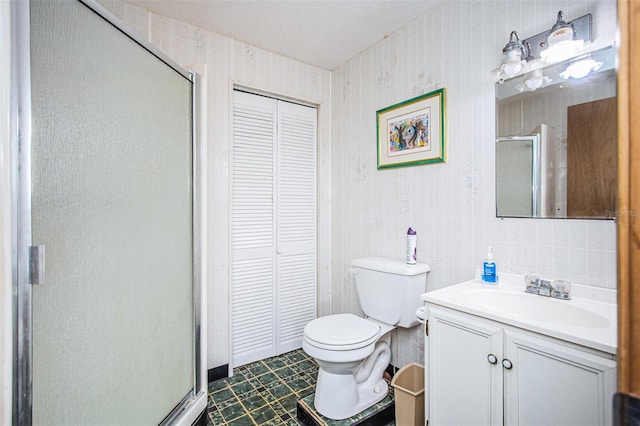 bathroom featuring tile walls, vanity, a shower with shower door, and toilet