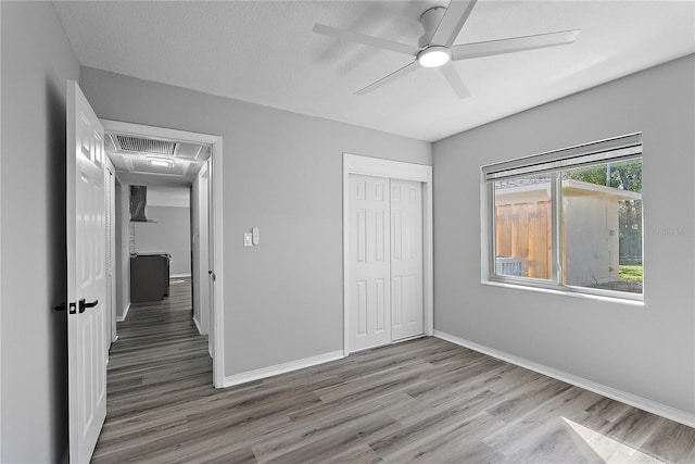 unfurnished bedroom with hardwood / wood-style floors, a textured ceiling, a closet, and ceiling fan