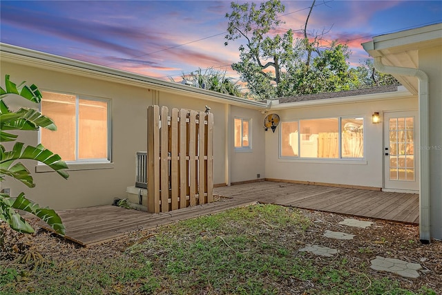 back house at dusk featuring a deck