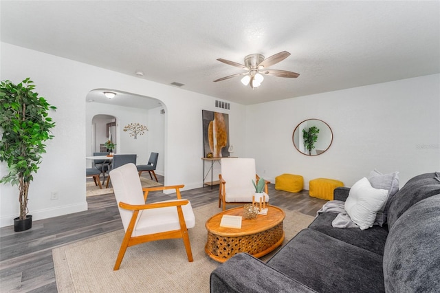 living room featuring dark wood-type flooring, a textured ceiling, and ceiling fan