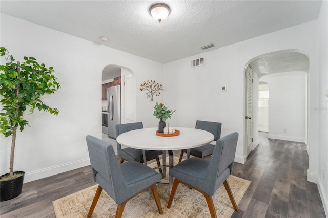 dining space featuring a textured ceiling and dark hardwood / wood-style flooring