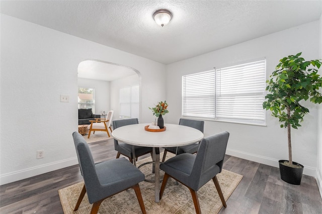 dining space featuring dark wood-type flooring and a textured ceiling