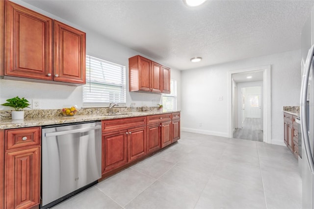 kitchen with dishwasher, sink, light stone countertops, light tile patterned flooring, and a textured ceiling