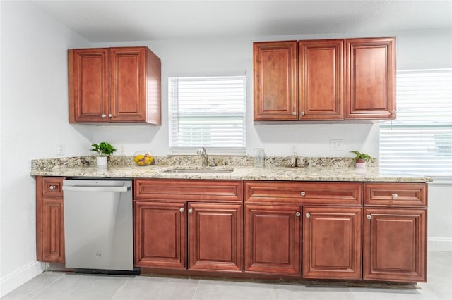 kitchen featuring light stone countertops, stainless steel dishwasher, sink, and light tile patterned floors