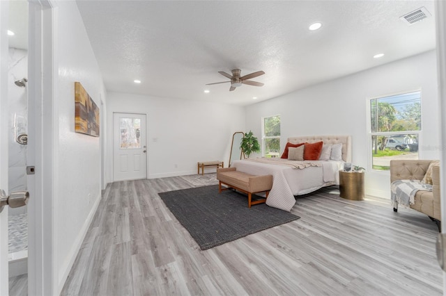 bedroom with light hardwood / wood-style flooring, a textured ceiling, and ceiling fan