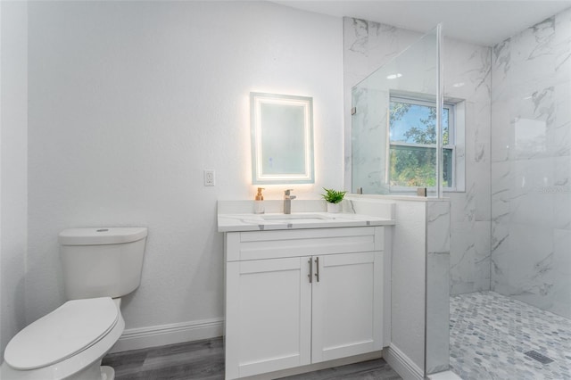 bathroom featuring vanity, hardwood / wood-style floors, tiled shower, and toilet