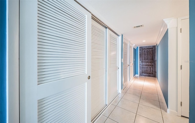 corridor with crown molding and light tile patterned floors