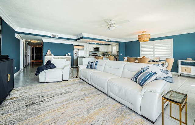 tiled living room with ceiling fan and crown molding