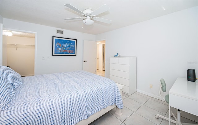 tiled bedroom with ceiling fan, a closet, and a spacious closet