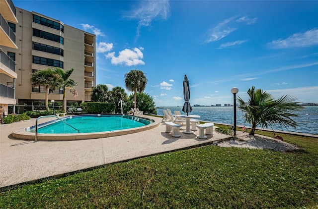 view of pool with a water view and a yard