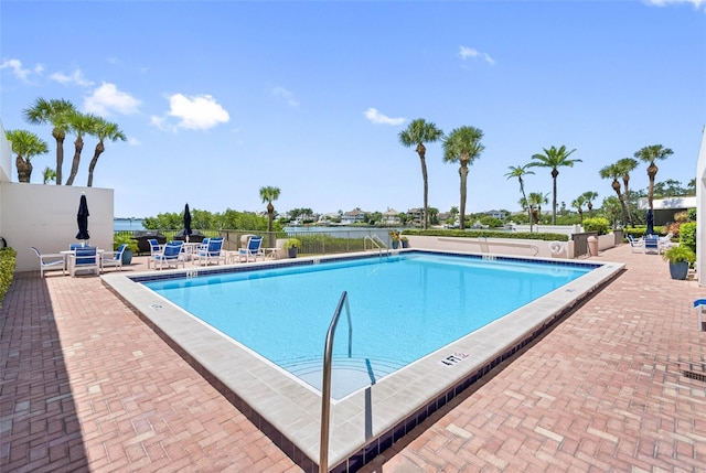 view of pool featuring a water view and a patio