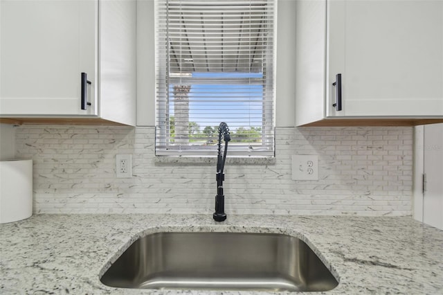 details featuring tasteful backsplash, sink, and white cabinets