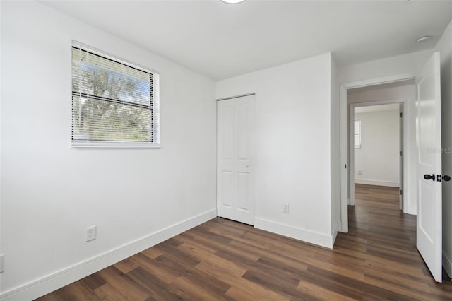 unfurnished bedroom with a closet and dark hardwood / wood-style floors