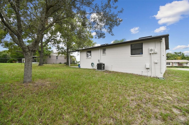 rear view of property with central AC unit and a lawn