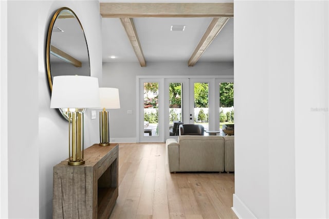 living room with french doors, beamed ceiling, and light hardwood / wood-style flooring