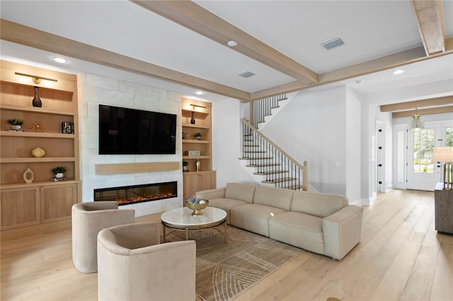 living room with beamed ceiling, a fireplace, and light wood-type flooring