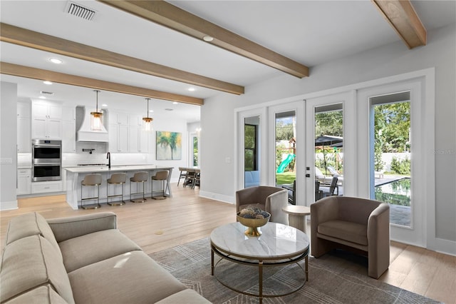 living room featuring beam ceiling and light wood-type flooring