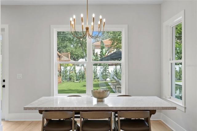 dining space with light hardwood / wood-style flooring, an inviting chandelier, and plenty of natural light