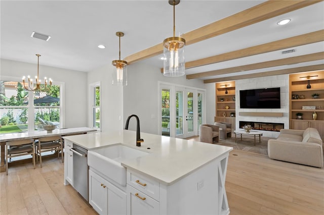 kitchen with decorative light fixtures, a wealth of natural light, and a kitchen island with sink