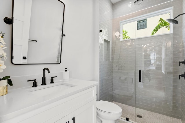 bathroom featuring toilet, a shower with shower door, and vanity