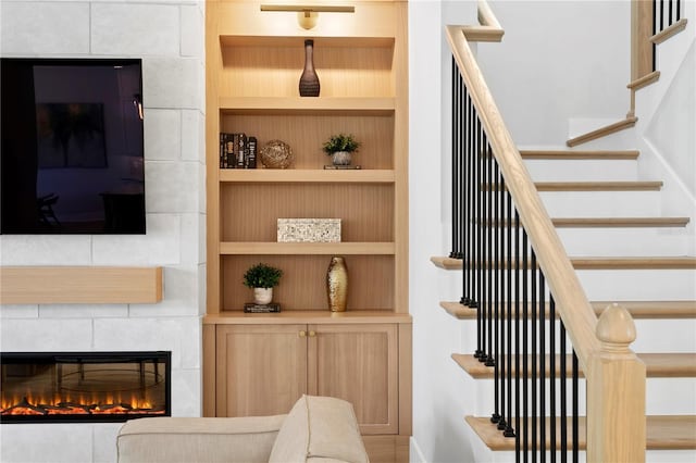 staircase featuring built in features and a tile fireplace