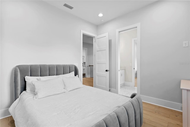 bedroom featuring light hardwood / wood-style floors and ensuite bath