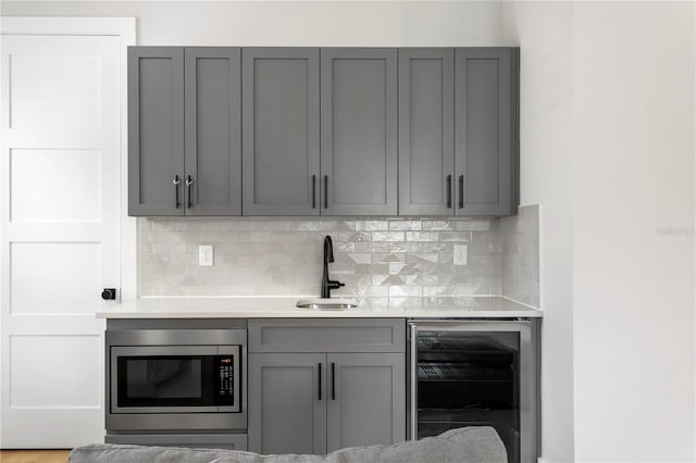 kitchen featuring wine cooler, gray cabinetry, and stainless steel microwave